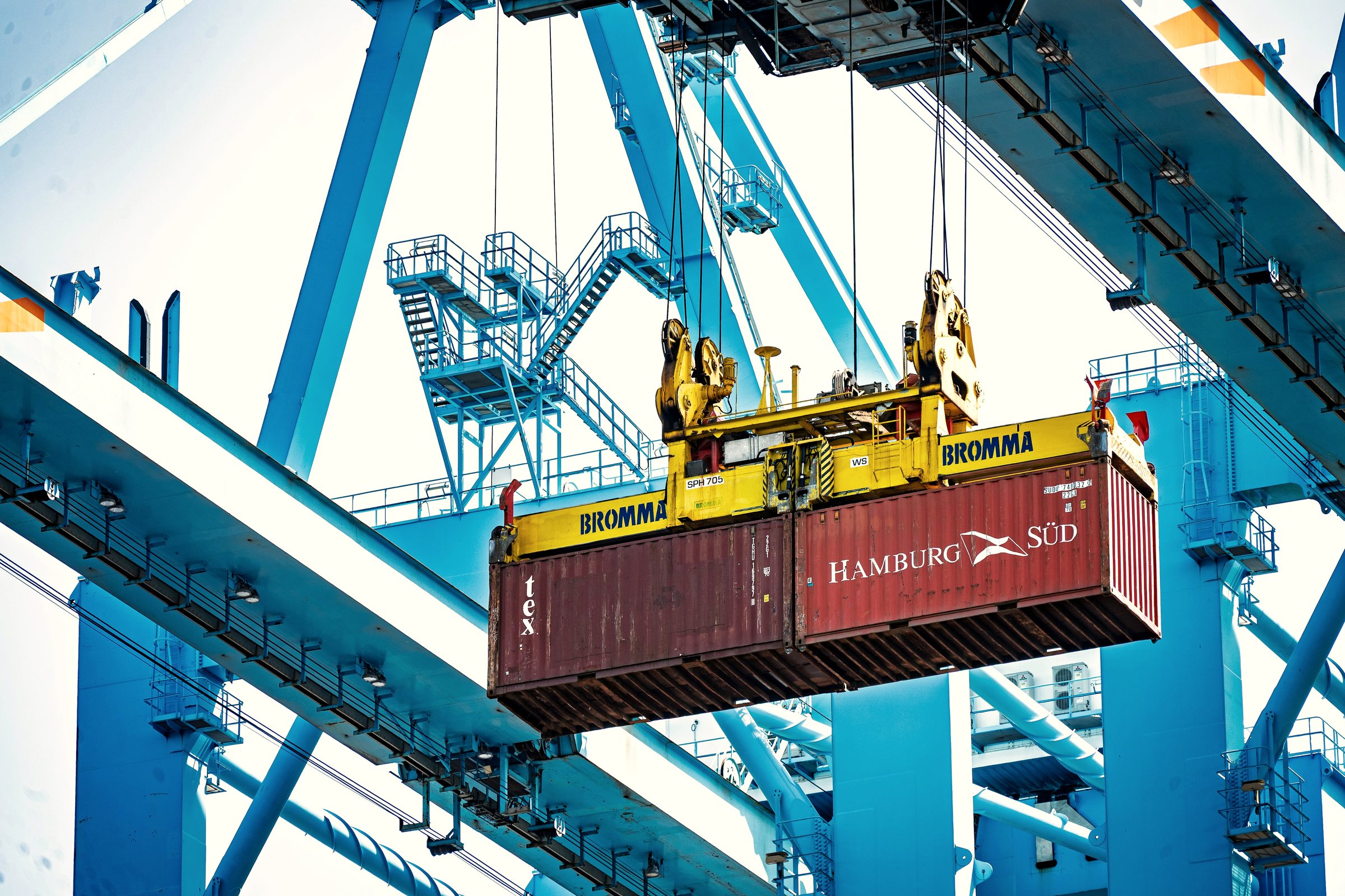 A container on a crane spreader being lifted at a container terminal